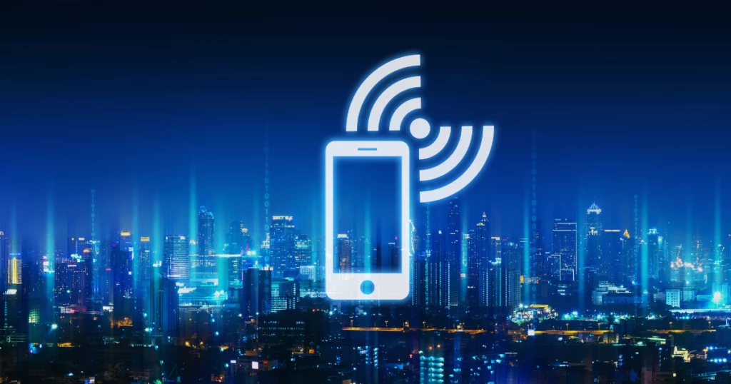 photo d'une ville la nuit avec pictogramme d'un téléphone en train de capter pour illustrer l'itinérance des données en europe.