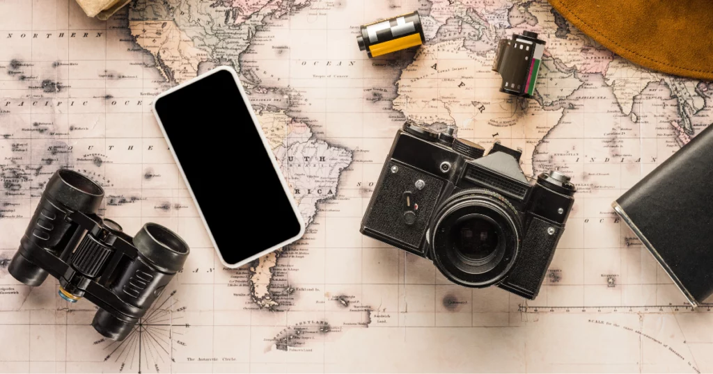 photo d'une carte en arrière plan avec un téléphone, un appareil photo, des jumelles et un chapeau pour illustrer le guide pour appeler la France depuis les USA