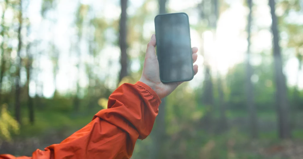 photo d'une main qui tient un téléphone en l'air pour capter le réseau avec une esim